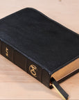 Black leather-bound book with gold embossed lettering on a wooden surface